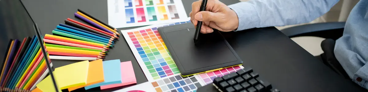 Hand zeichnet mit Grafiktablet neben Farbmustern und Farbkreis