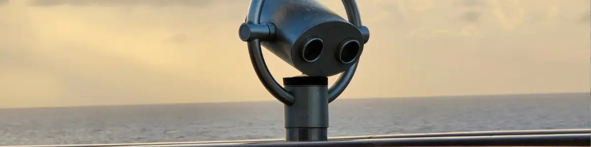 Münzfernrohr an einer Reling mit Blick aufs Meer im Abendlicht