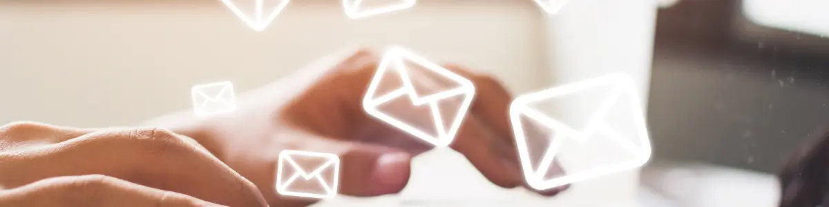 Hand tippt auf einer Laptop-Tastatur, umgeben von stilisierten E-Mail-Symbolen